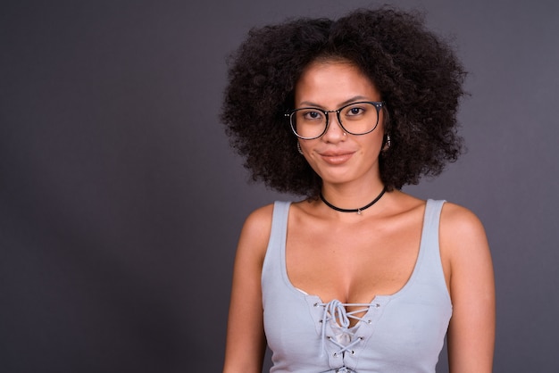  young multi ethnic African American woman with Afro hair against gray wall