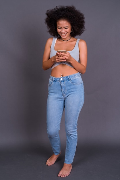  young multi ethnic African American woman with Afro hair against gray wall