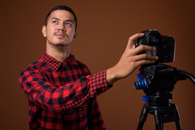 Young multi-ethnic Asian man against brown wall