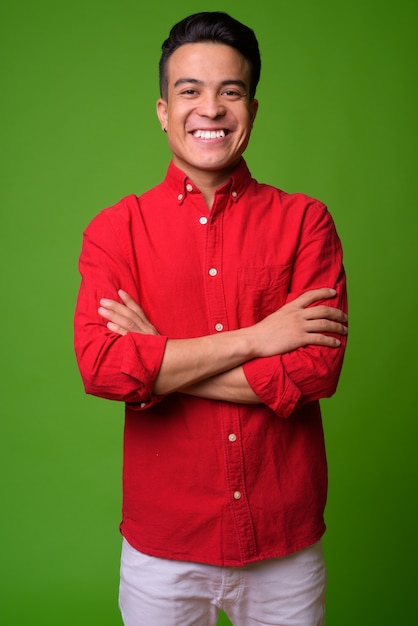 Young multi-ethnic businessman wearing red shirt against green background