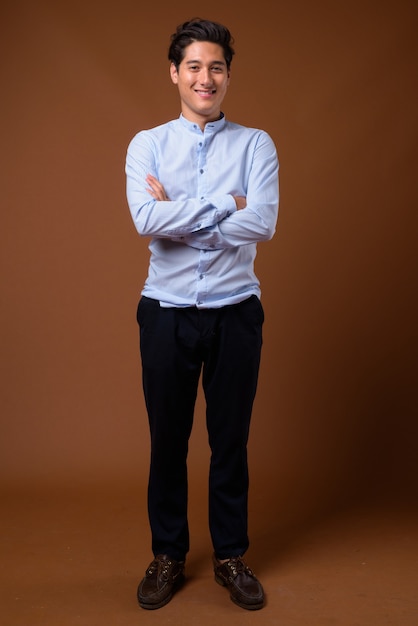 Young multi-ethnic handsome businessman against brown background