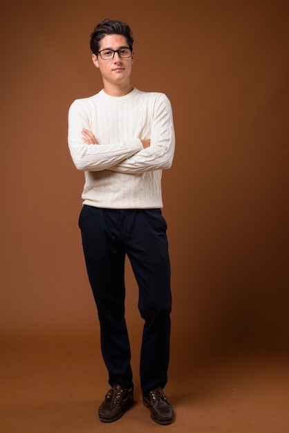 Young multi-ethnic handsome man against brown background