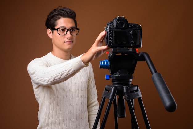 Young multi-ethnic handsome man against brown background