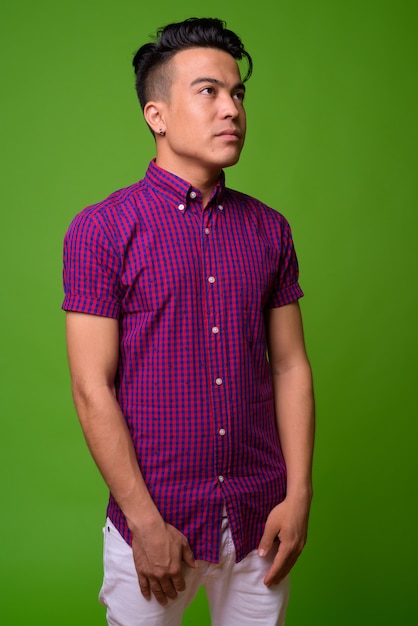 Young multi-ethnic man wearing purple shirt against green background