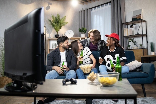 Young multi ethnic people watching football match on TV