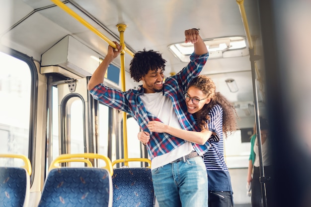 Young multicultural couple hugging in the public transport.