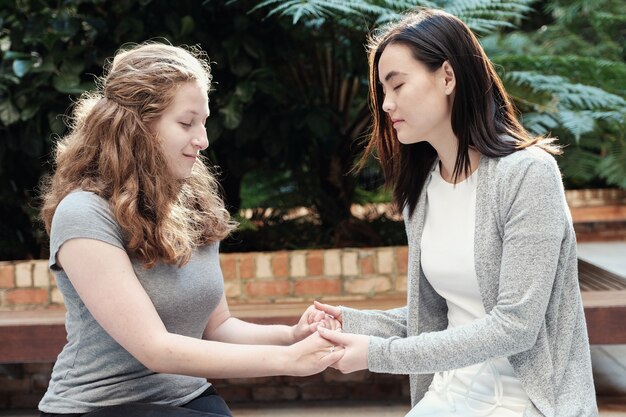 Photo young multicultural women holding hands while praying