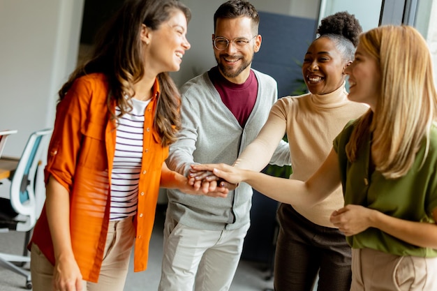 Young multiethnic startup team hold hands together at the modern office