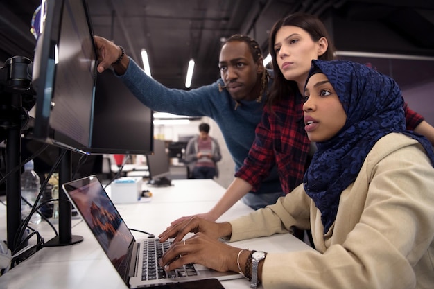 young multiethnics business team of software developers working together using laptop computer while writing programming code at modern startup office