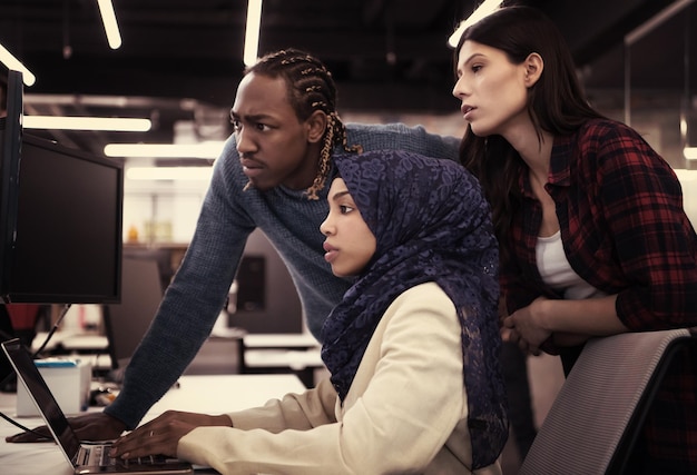 young multiethnics business team of software developers working together using laptop computer while writing programming code at modern startup office