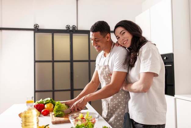 young multiracial couple prepares veggie salad in white modern kitchen