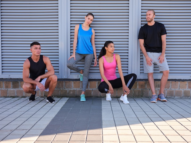 Young multiracial friends in sportswear standing near wall