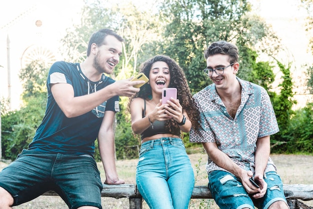 Young multiracial friends using smartphone at university\
college garden smiling young woman sharing video call with her\
friends at park technology concept with always connected gen z\
friends
