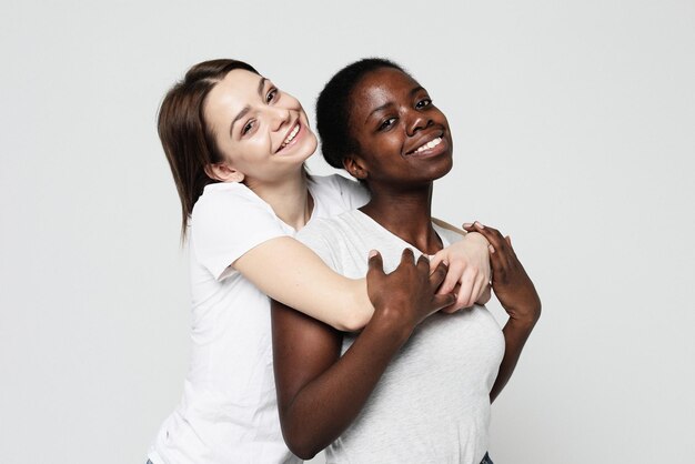 Young multiracial women standing together and smiling at camera isolated over white background