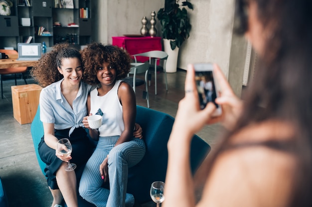 young multiracial women taking photo and having fun in modern loft