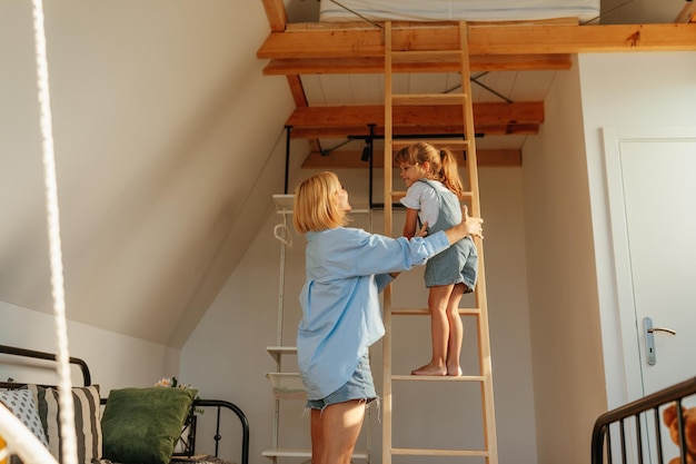 娘がはしごに登るのを手伝う若い母親