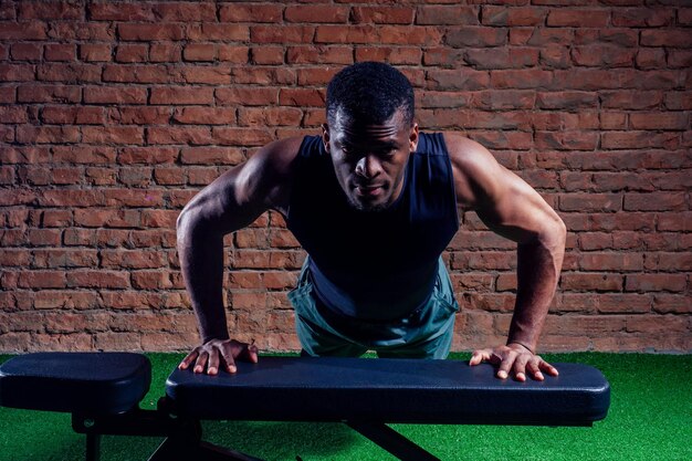 Young muscular african american man doing push-ups and looking away