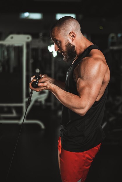 A young muscular bodybuilder man doing hard training for his arms muscles at the gym.