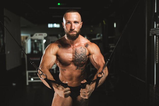 A young muscular bodybuilder man doing hard training for his chest muscles at the gym.