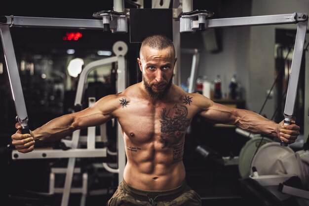 Un giovane bodybuilder muscolare che fa un duro allenamento per i muscoli del torace in palestra.