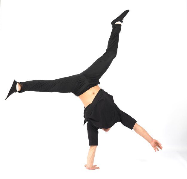 Young muscular breakdancer man stands on his hand He is wearing black clothes . white background