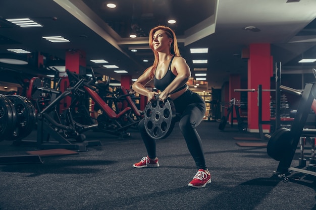 Young muscular caucasian woman practicing in gym with equipment wellness healthy lifestyle