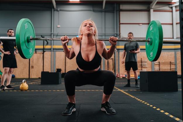 Young muscular girl lifting a dead weight barbell in a crossfit gymnasium