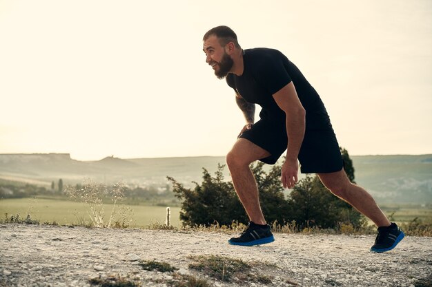 Young muscular male athlete running up the hill