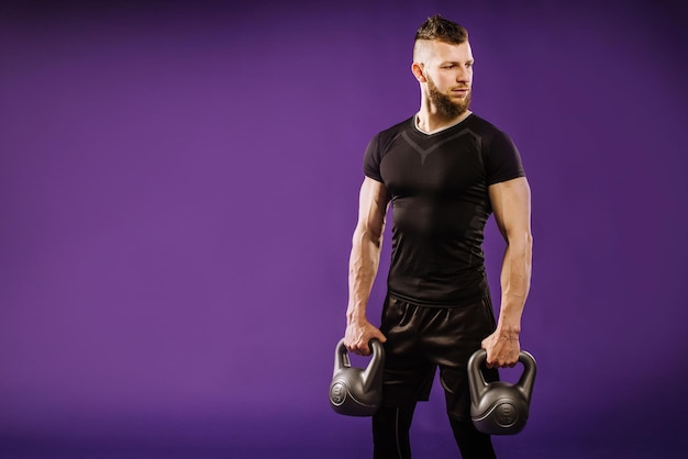 Young muscular man doing exercises with weight on purple studio background. Copy space