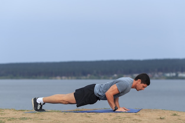 Young muscular man doing push-ups outdoors