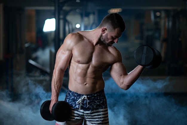 Young muscular man exercising with dumbbells