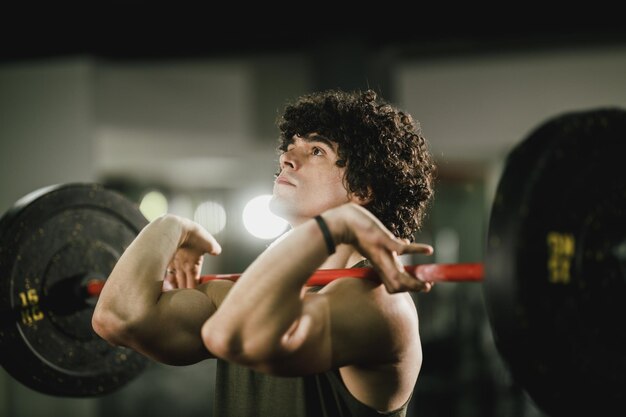 Photo a young muscular man is doing hard training with barbell at the gym.