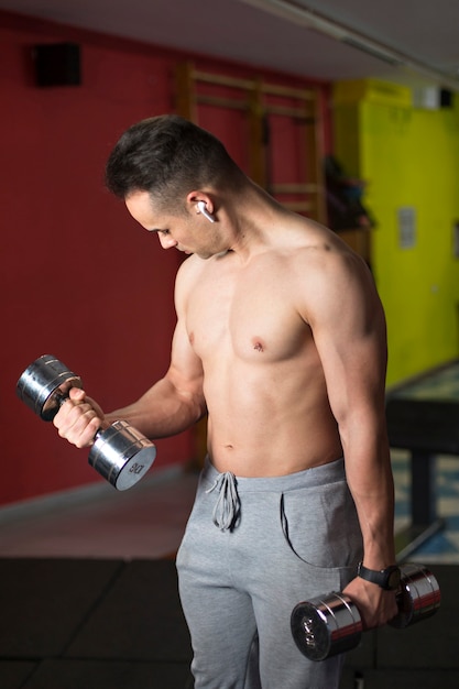 Young muscular man performing dumbbell exercise