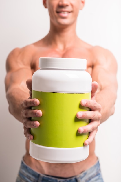 Young muscular man with jar of protein.