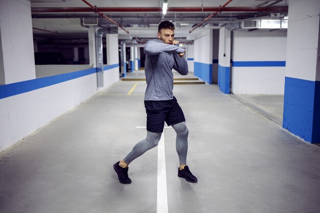 Young muscular sportsman sparring in underground garage.