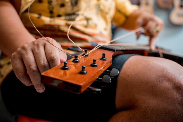 Giovane musicista che cambia le corde su una chitarra classica in un negozio di chitarre