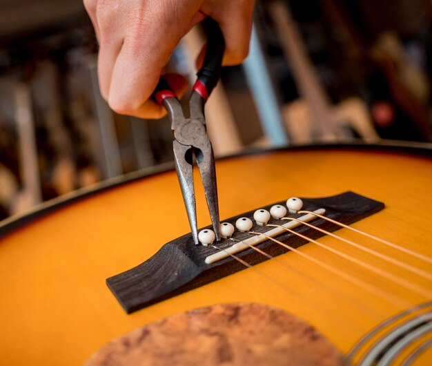 Молодой музыкант меняет струны на классической гитаре в гитарном магазине