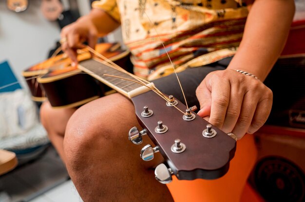 젊은 음악가 가 기타 가게 에서 클래식 기타 의 현 을 바꾸고 있다