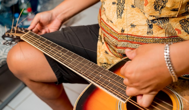 Young musician changing strings on a classical guitar in a guitar shop