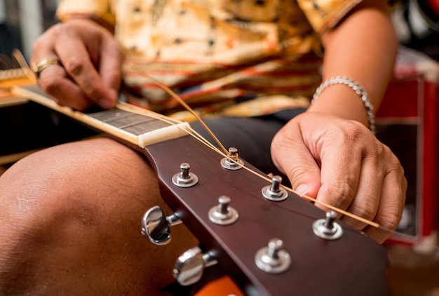 Молодой музыкант меняет струны на классической гитаре в гитарном магазине