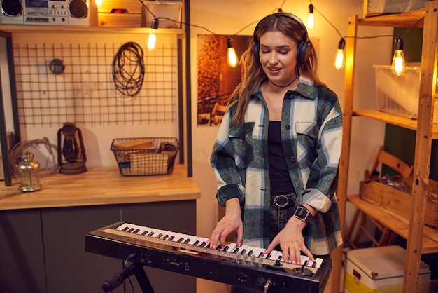 Young musician in headphones playing on electric piano in the studio