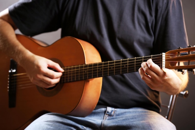 Young musician playing acoustic guitar close up