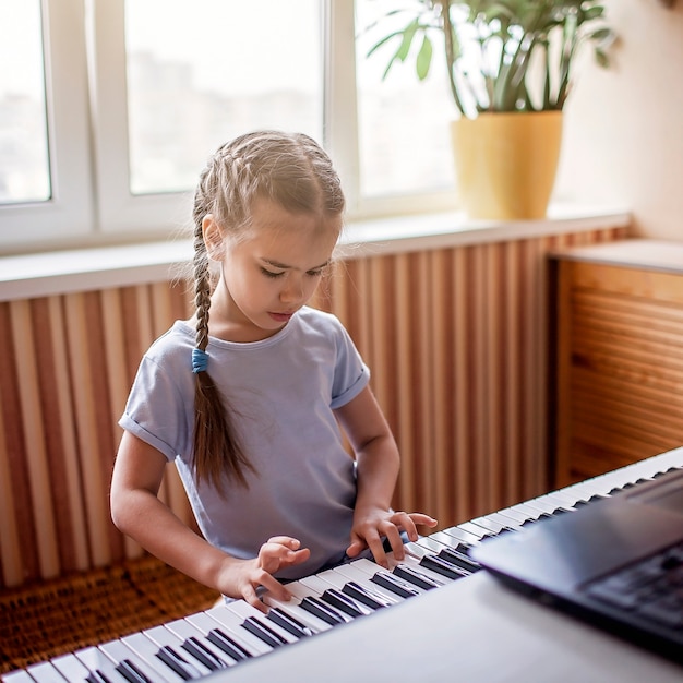 Young musician playing classic digital piano at home during online class at home, self-isolation