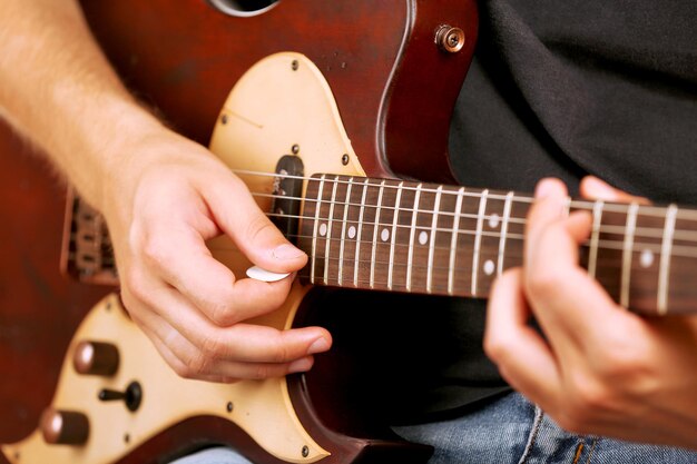 전기 기타를 연주하는 젊은 음악가를 닫습니다.