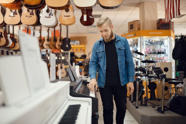 Young musician poses at the piano in music store