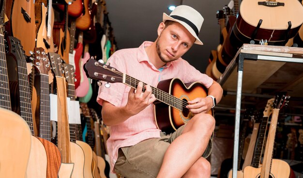 Young musician testing classical guitar in a guitar shop