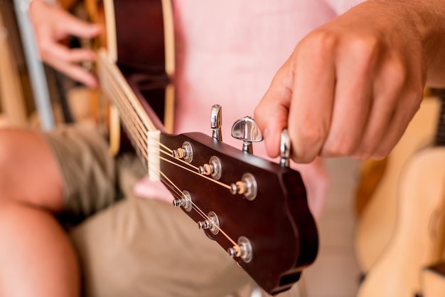 Молодой музыкант настраивает классическую гитару в гитарном магазине