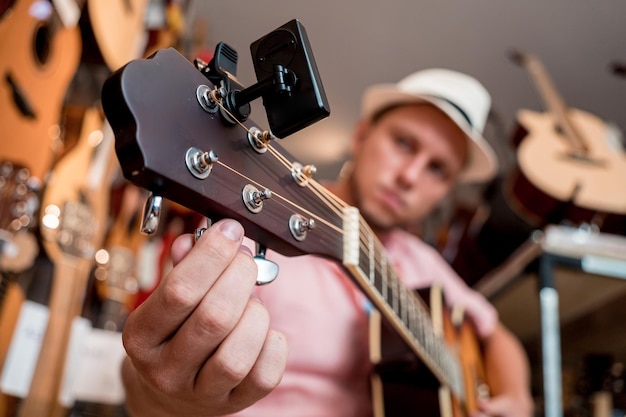 Foto giovane musicista che accorda una chitarra classica in un negozio di chitarre