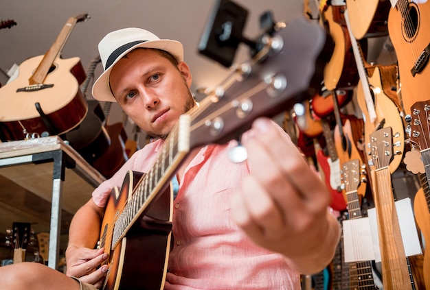 Young musician tuning a classical guitar in a guitar shop