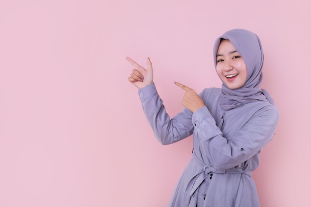 A young Muslim girl pointing to her left side